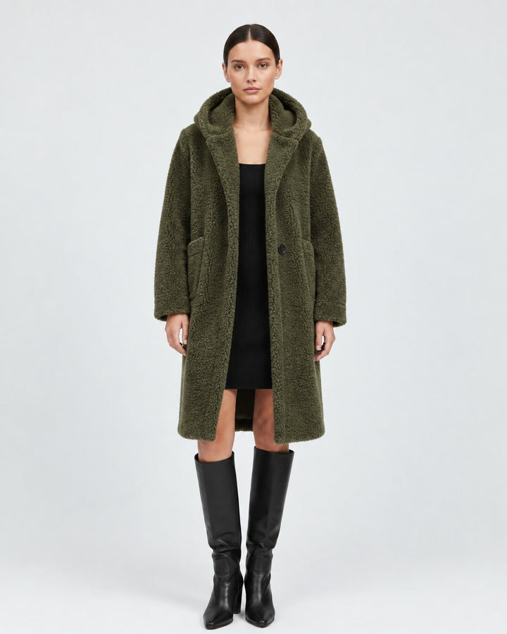 Luna Moda olive green hooded wool teddy coat with patch pockets, worn by a model over a black dress and boots.