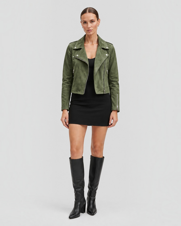 Luna Moda olive green suede biker jacket with silver zippers worn by a model over a black dress and knee-high boots