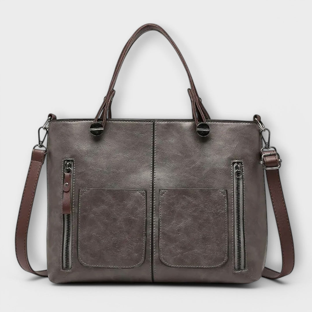 Luna Moda Olivera grey leather handbag with dual front zipper pockets, sturdy handles, and a detachable shoulder strap.