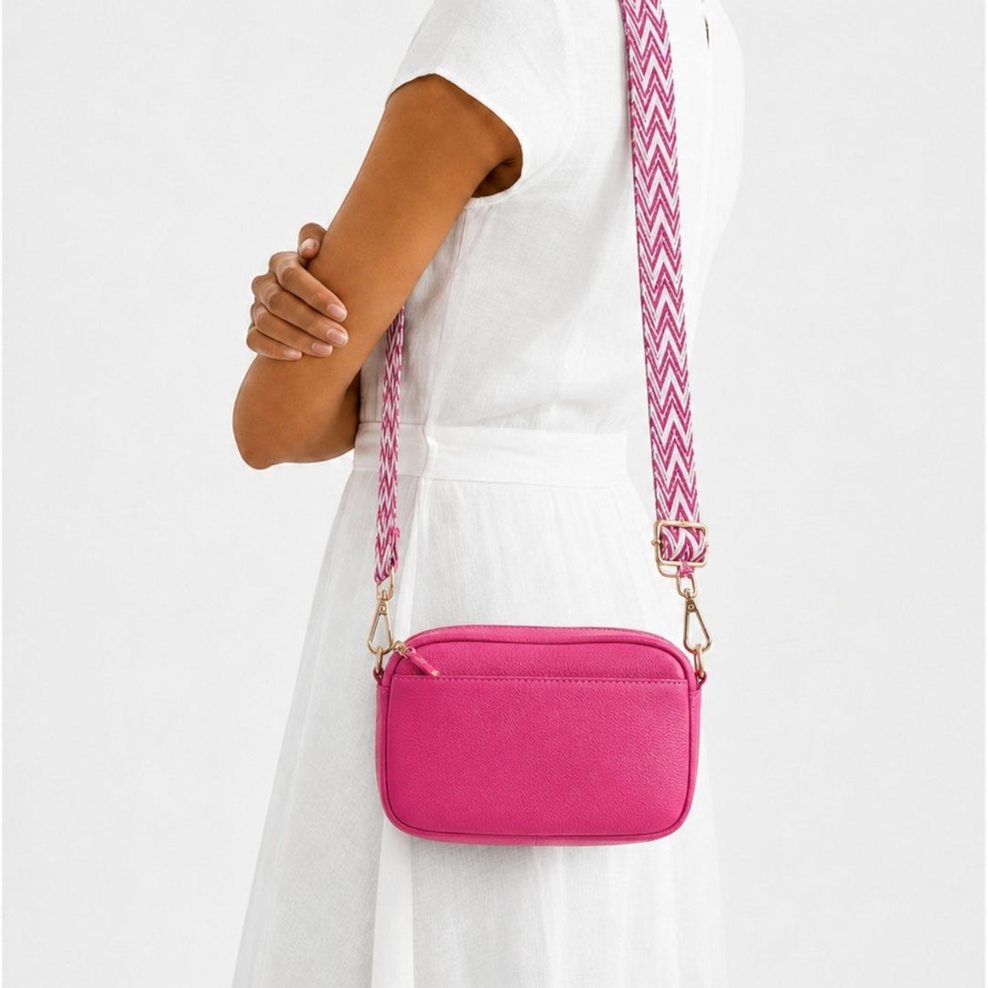 Luna Moda hot pink rectangular crossbody bag with a patterned chevron strap worn by a woman in a white dress