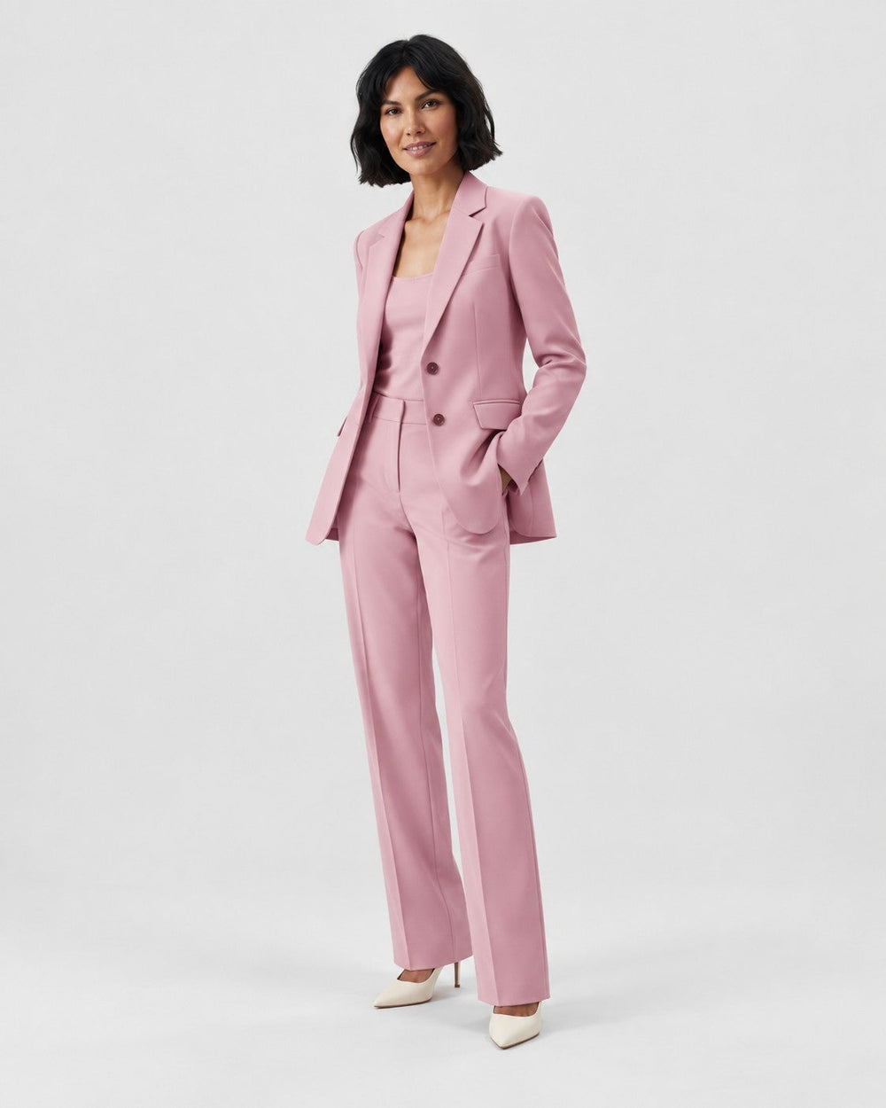 Luna Moda pink structured blazer and tailored trouser suit worn by a woman with white heels on a light background.