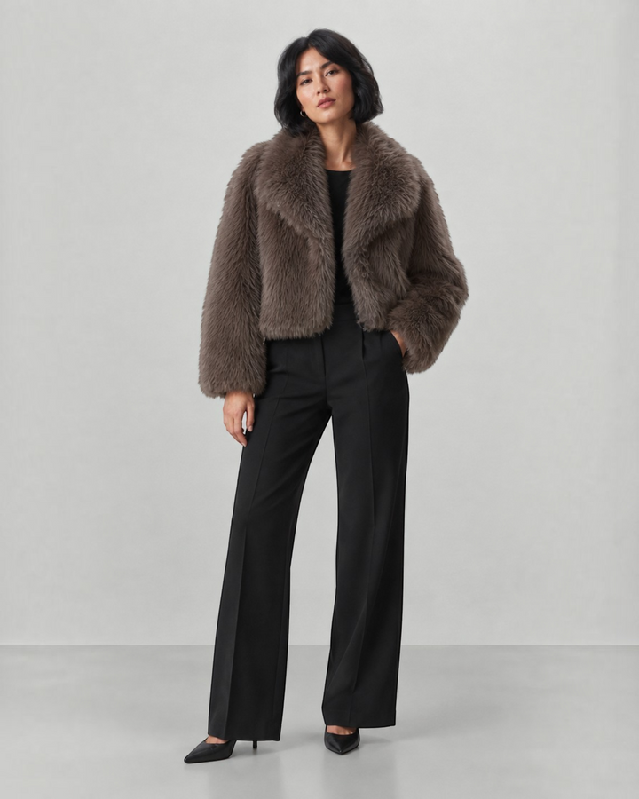 Luna Moda cropped faux fur coat in taupe with a wide collar, worn by a model with black trousers and heels.