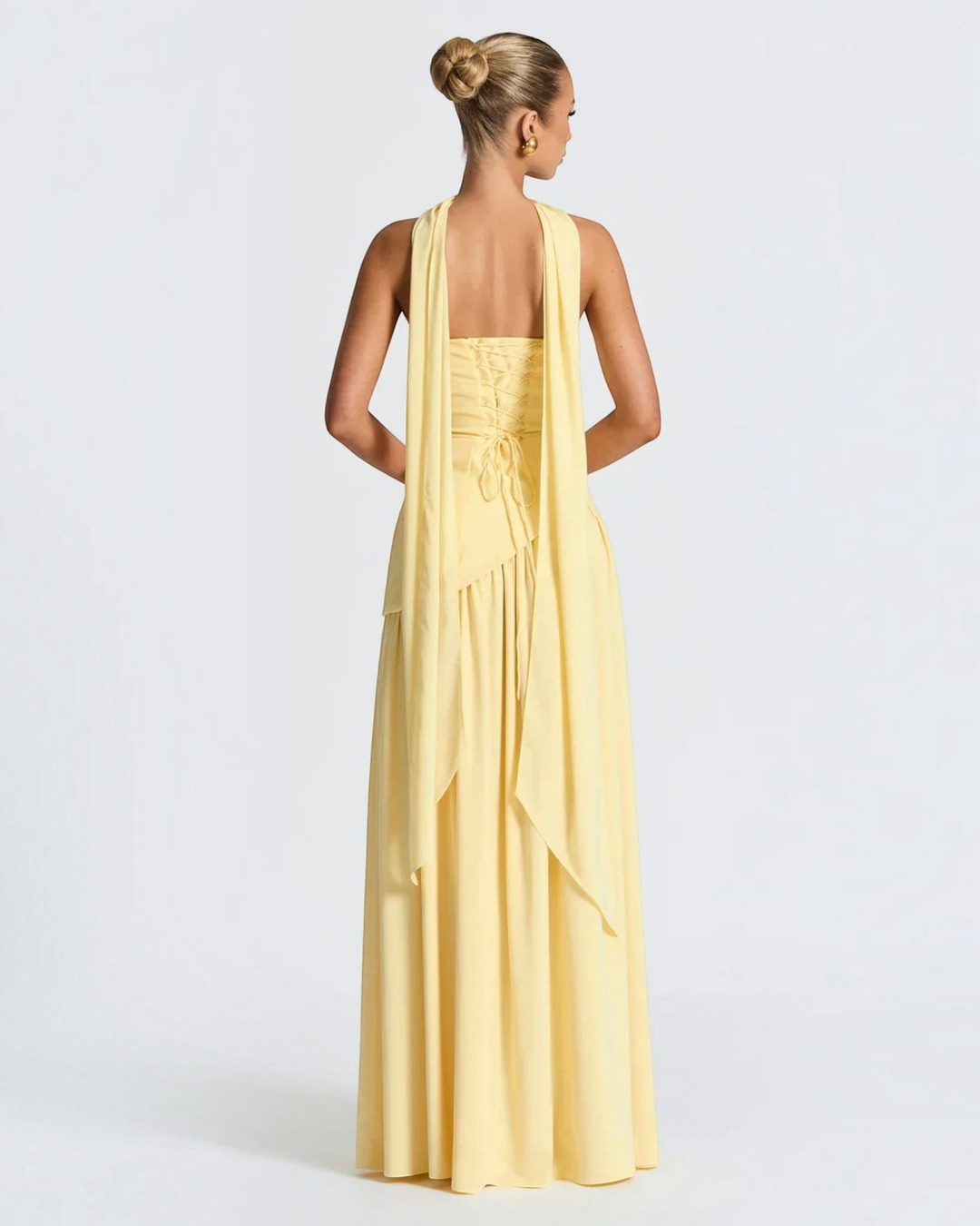 Luna Moda Zadie yellow maxi dress with halter neck, open back, and corset-style lace-up detail on a model