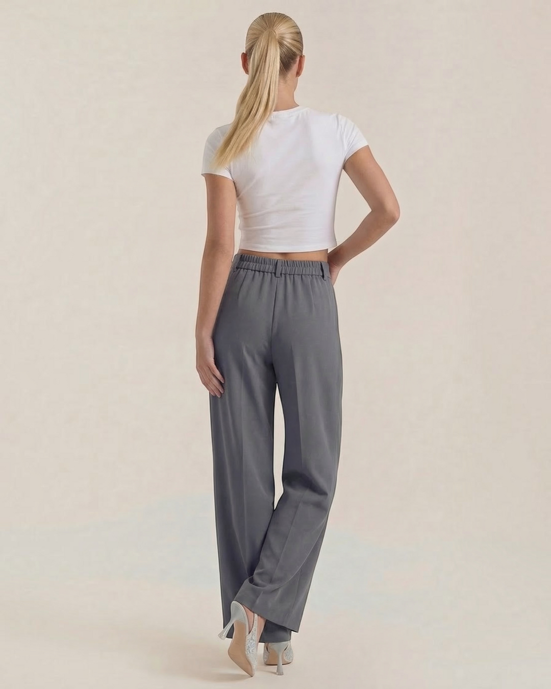 Luna Moda high-waisted grey palazzo trousers with a fluid, wide-leg fit worn by a model from the back view.