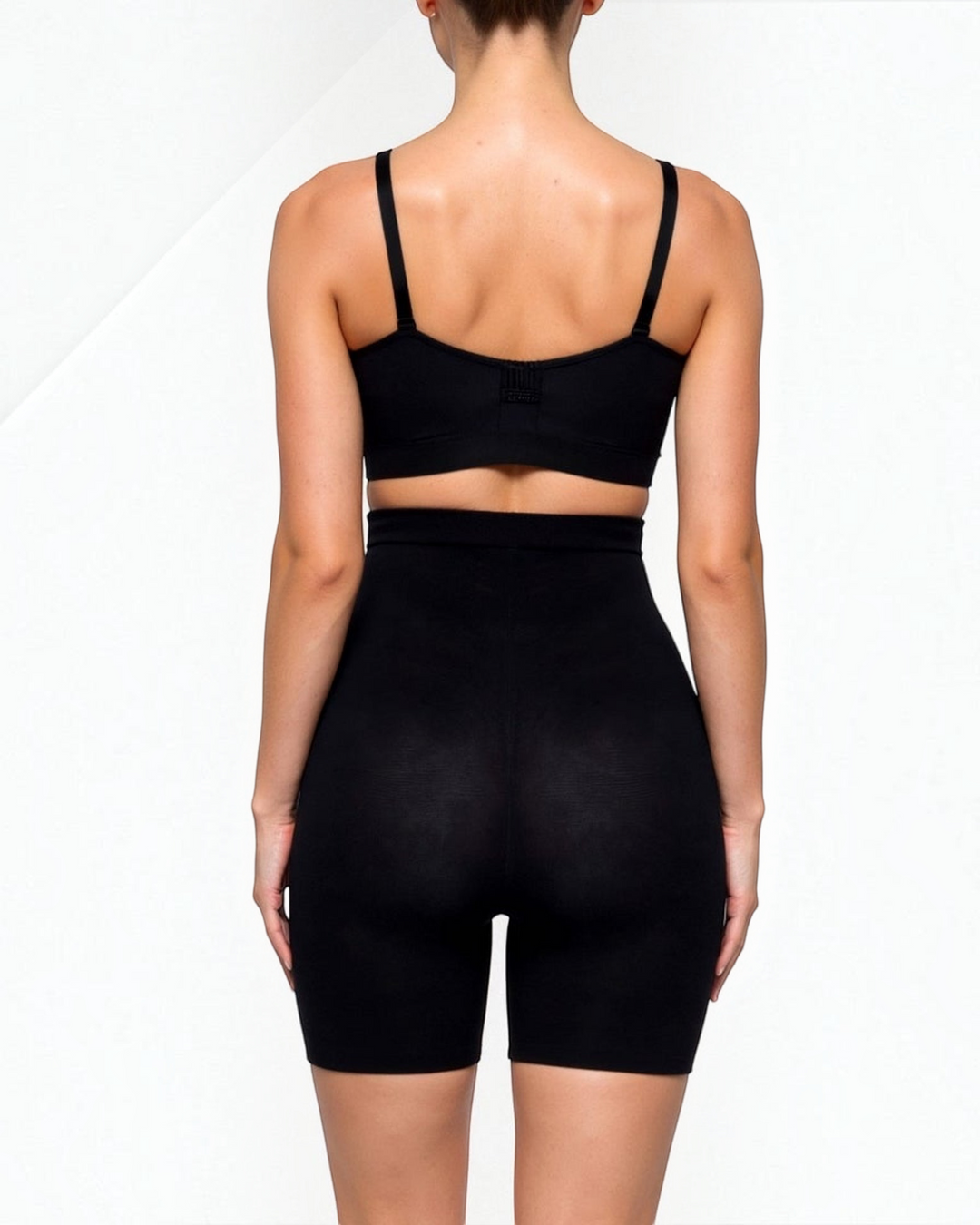 Luna Moda high-waisted seamless black shaping shorts reaching the knee, worn by a model from the back view.