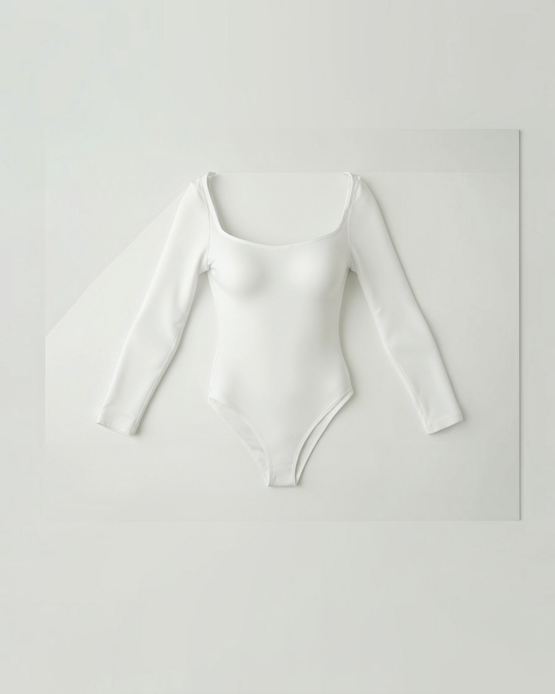 Luna Moda white long-sleeve seamless thong bodysuit with a scoop neck and ultra-thin compressive second-skin fabric.