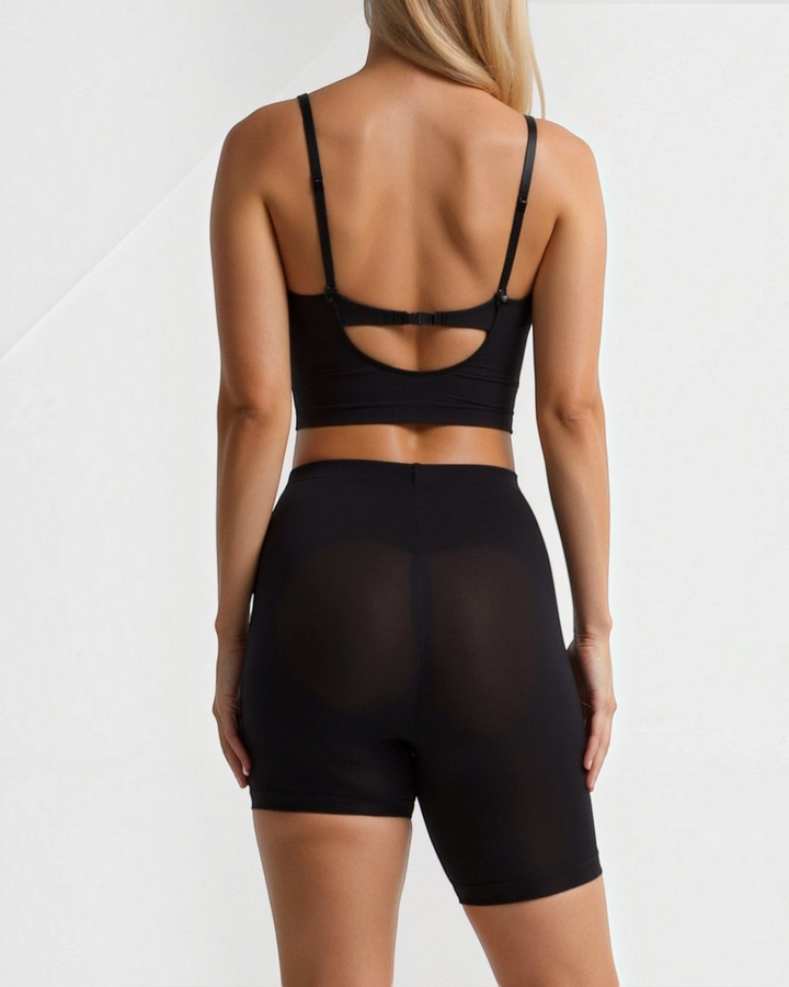 Luna Moda high-waisted seamless black shaping shorts with an asymmetrical left leg design worn by a woman from behind.